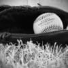 a black and white photo of a baseball in a baseball mitt