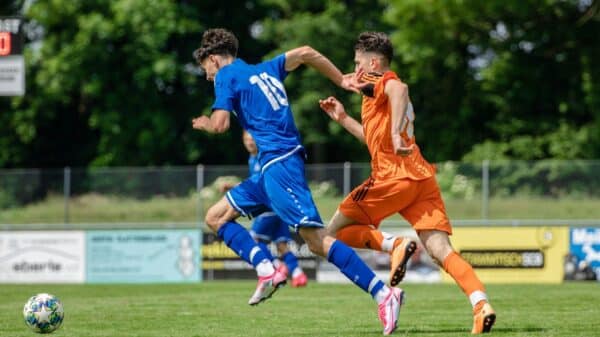 man in blue and orange jersey shirt running on green grass field during daytime